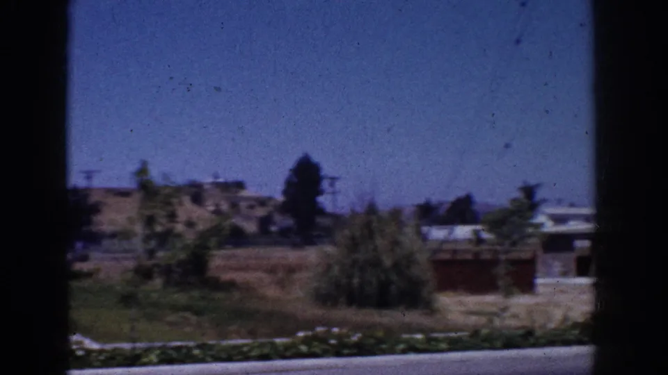 Yorba Linda suburban landscape with dry ground, low houses, utility lines, trees, and a dark window divider in the foreground.