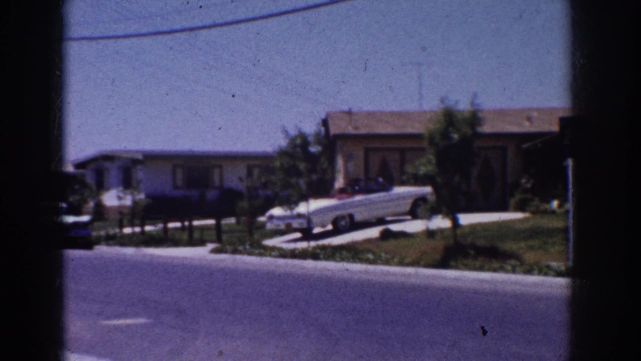 1962 Yorba Linda suburban street with single-story homes, manicured lawns and a white convertible parked in a driveway.