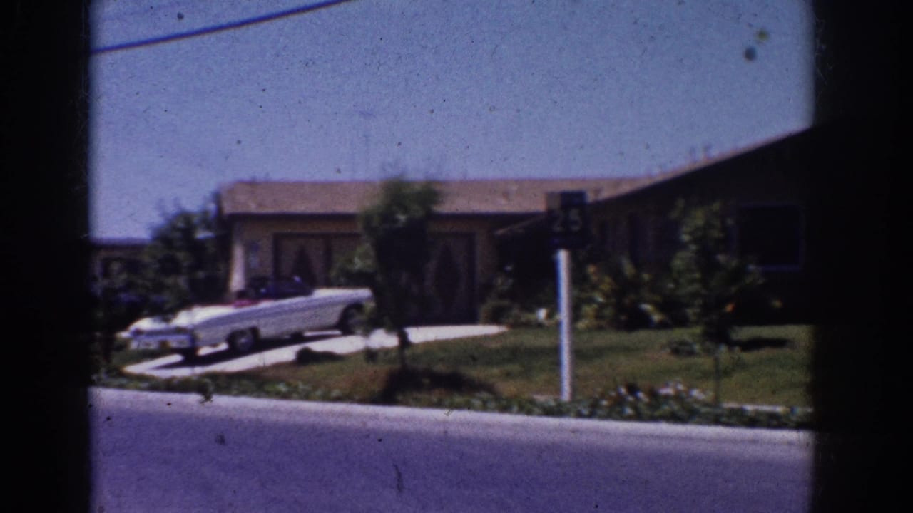 Ranch-style house, driveway, white convertible and a 25 mph street sign.