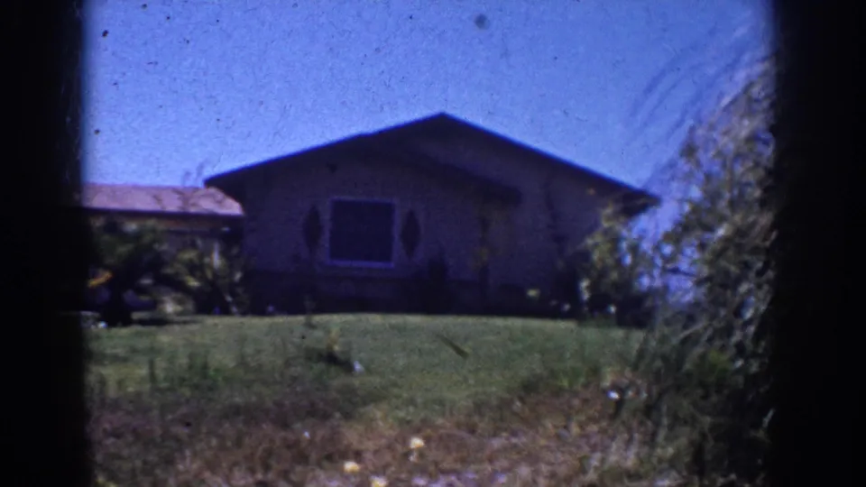 1962 Yorba Linda frame centering the single-story house, front window, lawn, ornamental planting, and visible 8mm frame borders.