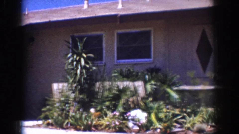 Yorba Linda residential exterior with a garden bed, dark doorway, windows, and diamond-shaped wall decoration.