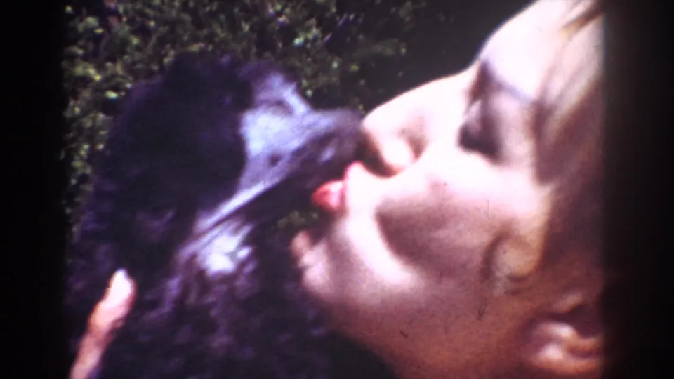 The puppy reaches toward the woman's face in an affectionate close-up from the 1962 Yorba Linda yard footage.