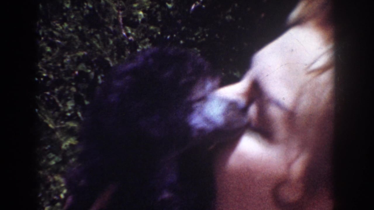 Small dark dog presses near a woman's face in close profile.