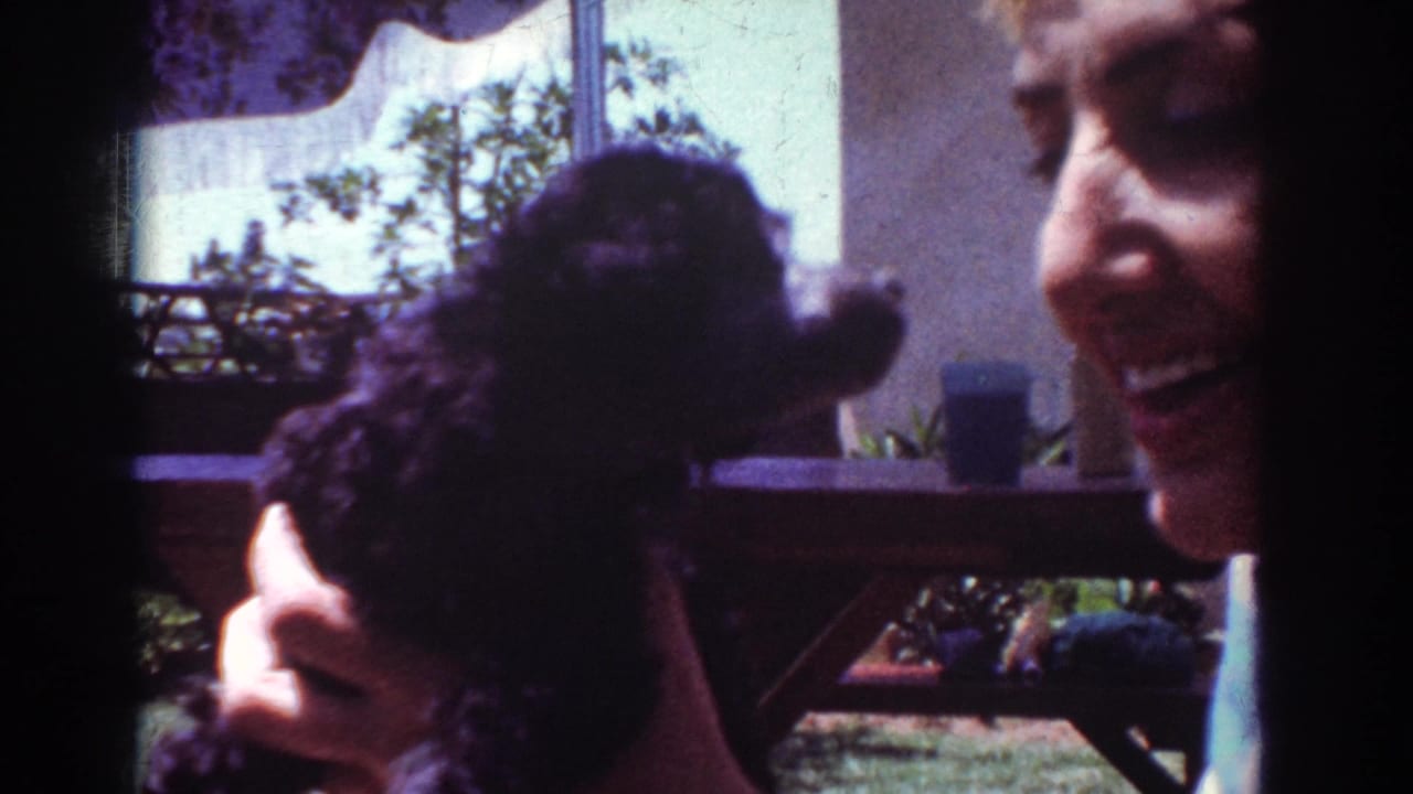 Woman smiling while holding a small black poodle outdoors.