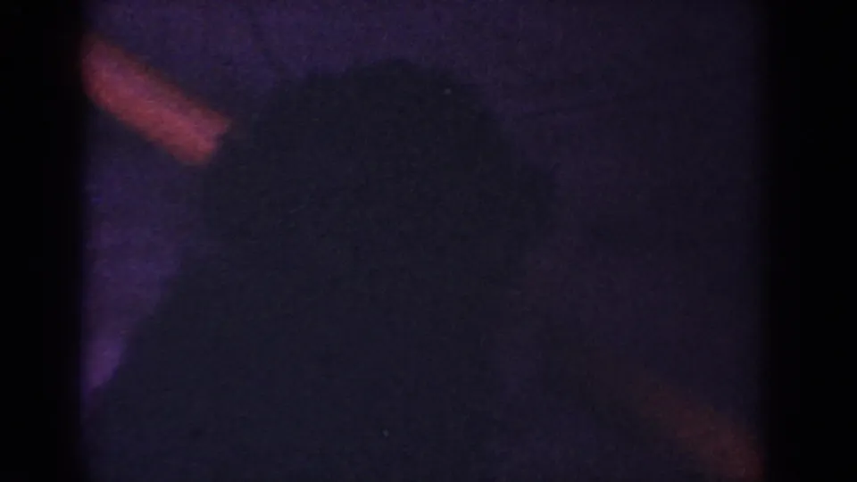 The final frame is very dark and underexposed, with a black puppy form barely visible against a shadowed area of the home-movie footage.