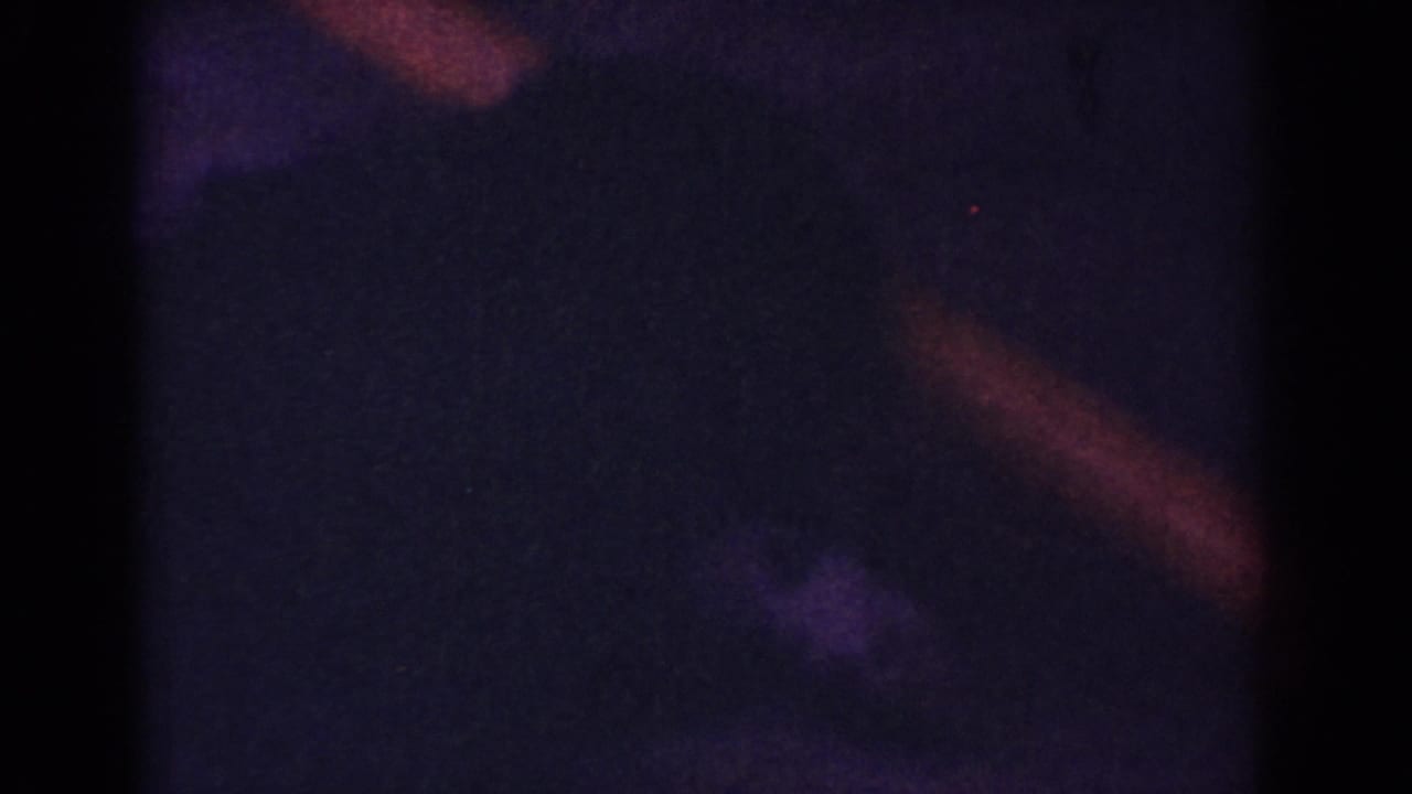 Very dark frame with faint reddish streaks and indistinct shadow shapes.