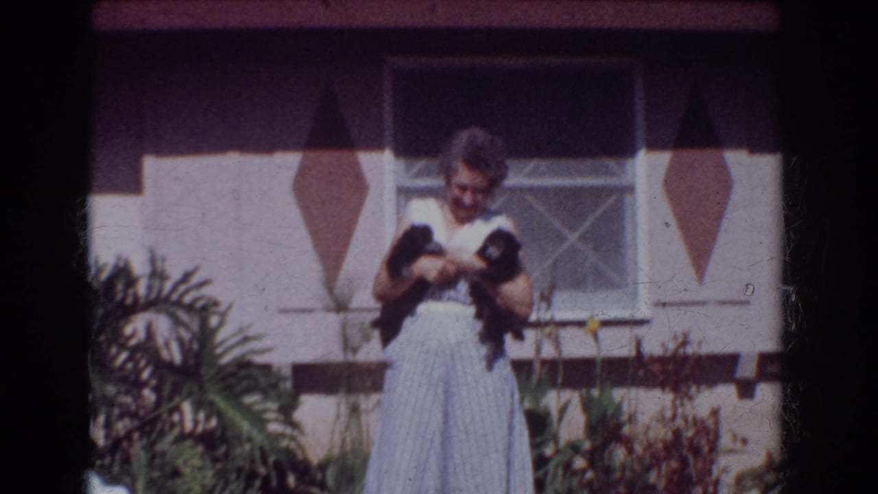 The 1962 Yorba Linda frame shows a woman holding two small dogs near a house window, with tropical garden plants in the foreground.