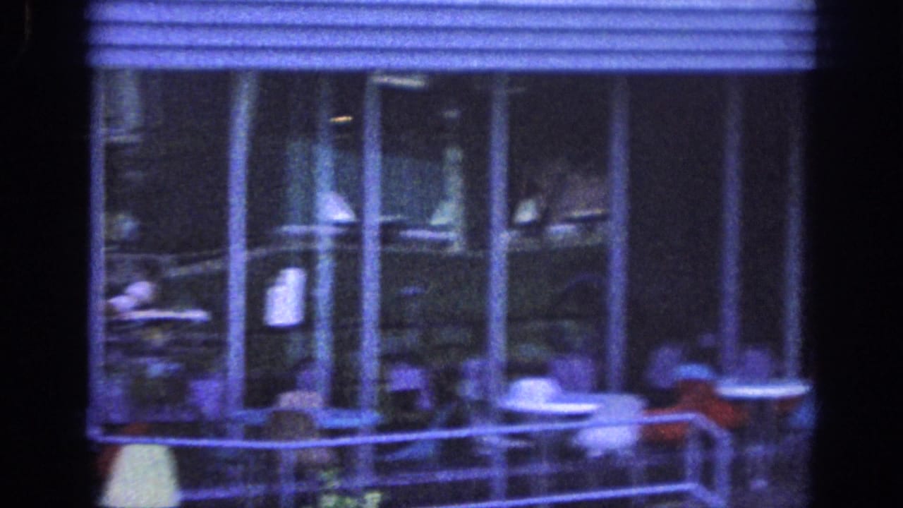 Upper balcony with glass doors, chairs, tables, and a person partly visible near the railing.