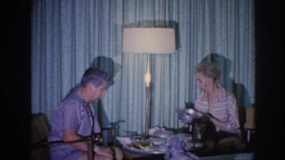 1963 Memphis domestic meal scene with an elderly woman serving or adjusting food while an elderly man sits nearby.