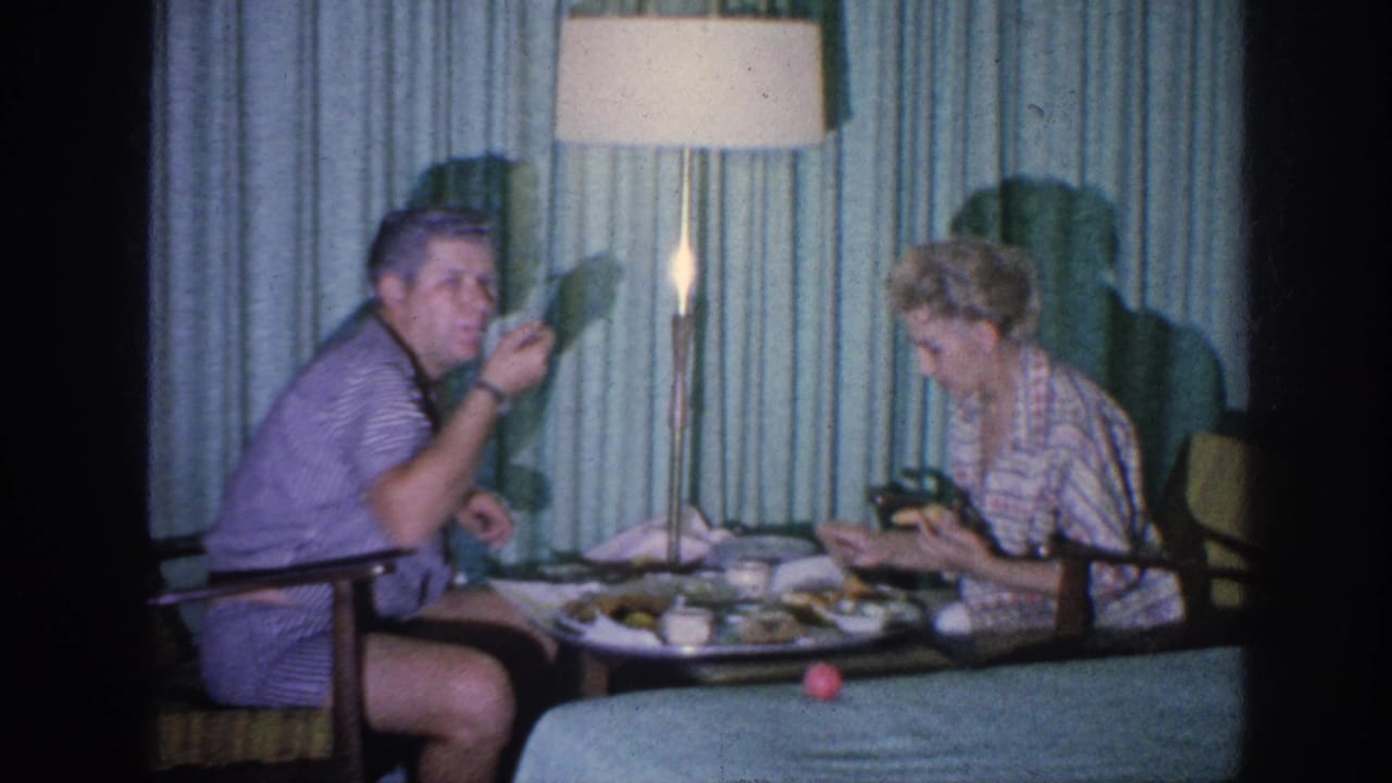 The seated man eats while the woman focuses on her meal in the curtained 1963 Memphis interior.