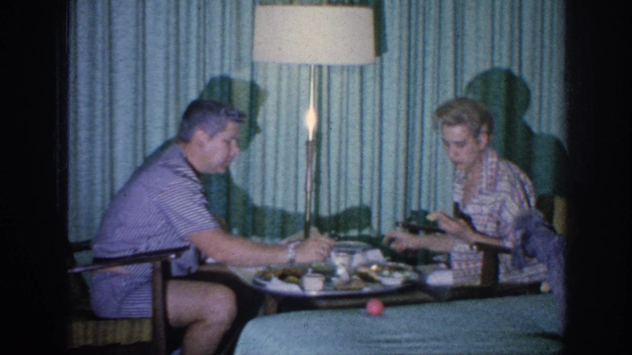 Man reaches toward the tray while a woman looks down at food or dishes.