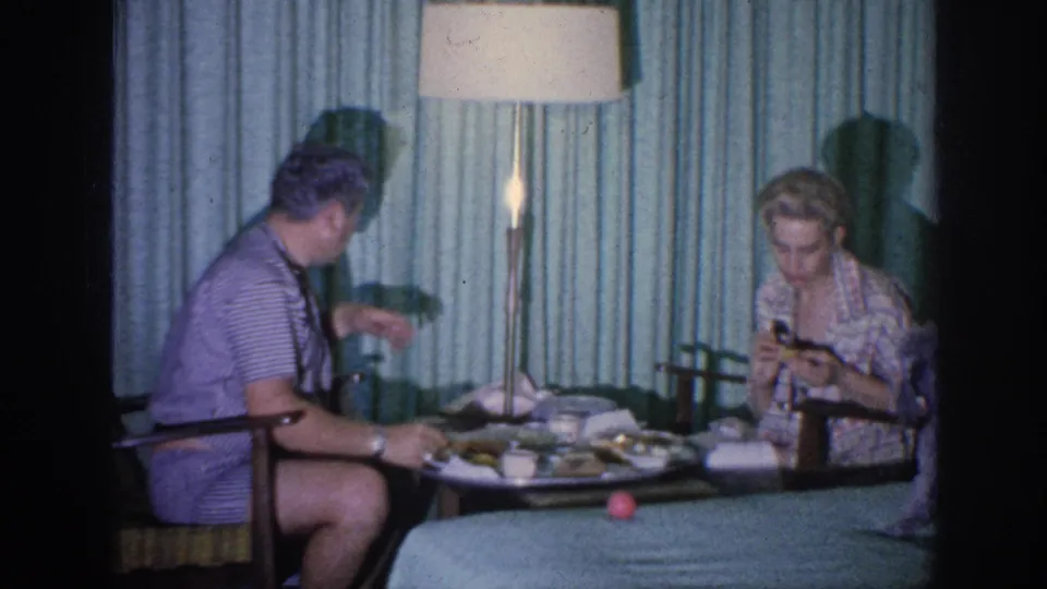 The man gestures from his chair as the woman looks down at her food in the 1963 Memphis interior.