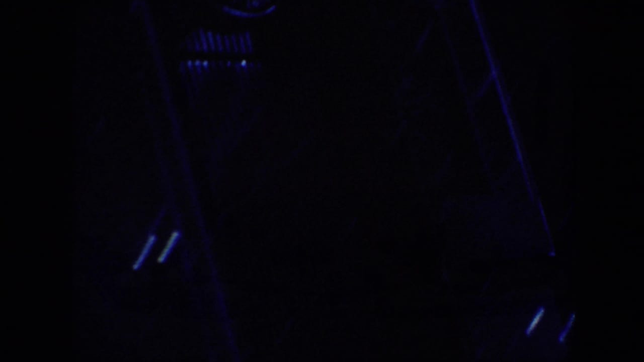 1963 home-movie frame from the Memphis travel clip showing a mostly dark interior edge with faint blue reflections and film grain.