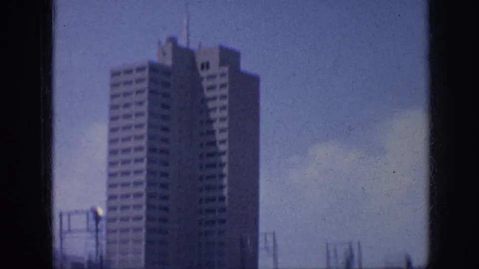 Memphis 1963 downtown view with a tall office building, dark window framing, blue sky, and soft 8mm film texture.