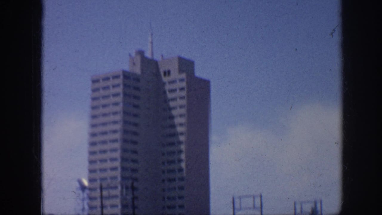 Tall mid-century building seen against a blue sky with utility poles in the foreground.