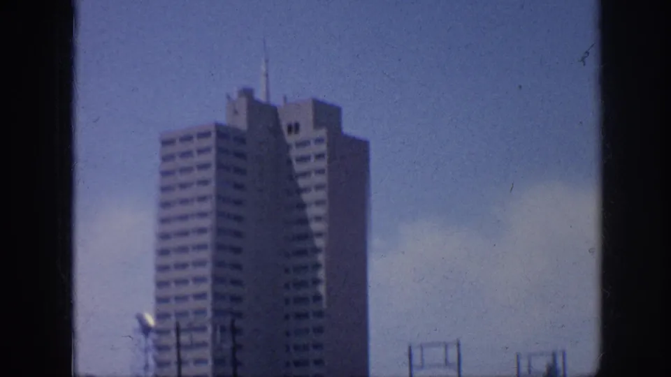A tall stepped mid-century building in Memphis, Tennessee, seen in soft 8mm focus against a blue sky with poles and street hardware below.