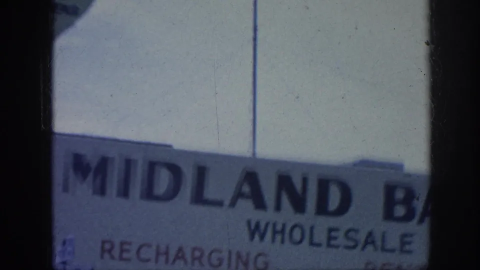 Close cropped Memphis storefront view showing large Midland Battery Co. lettering with partial wholesale and recharging text visible on the wall.