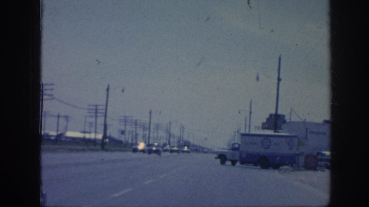 Roadway lined with utility poles and wires, with cars approaching and a commercial truck at right.