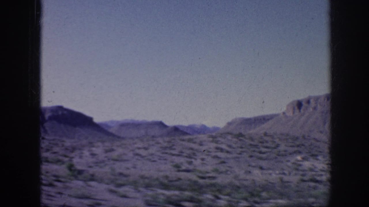 Open desert terrain with distant hills and dark vertical frame edges.