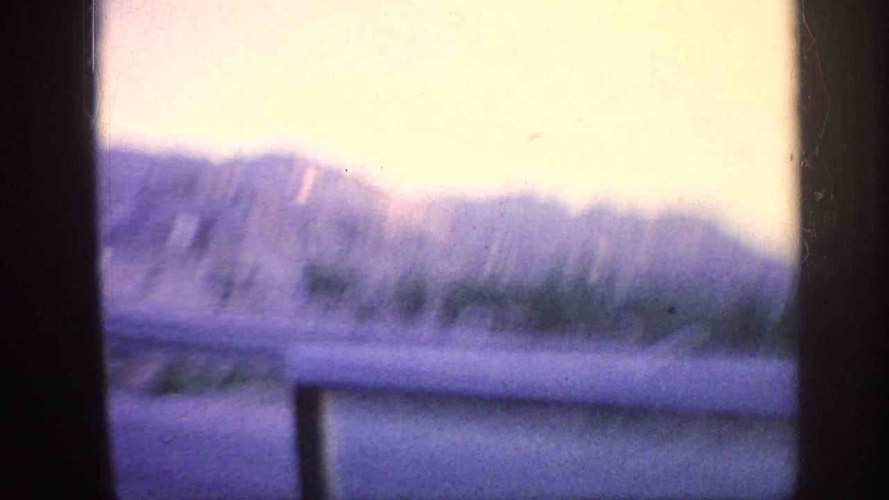 Blurred distant hills and pale sky seen through dark vertical frame edges.
