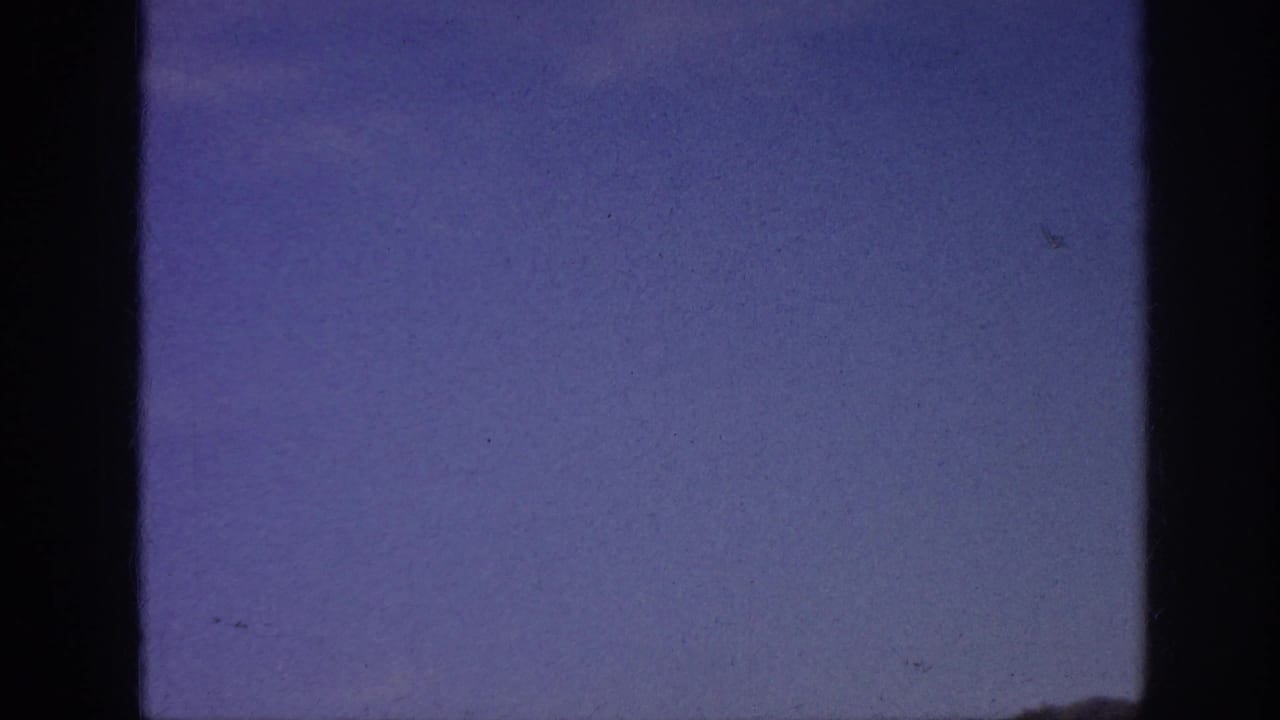 Blue sky and faint clouds framed by dark film edges.