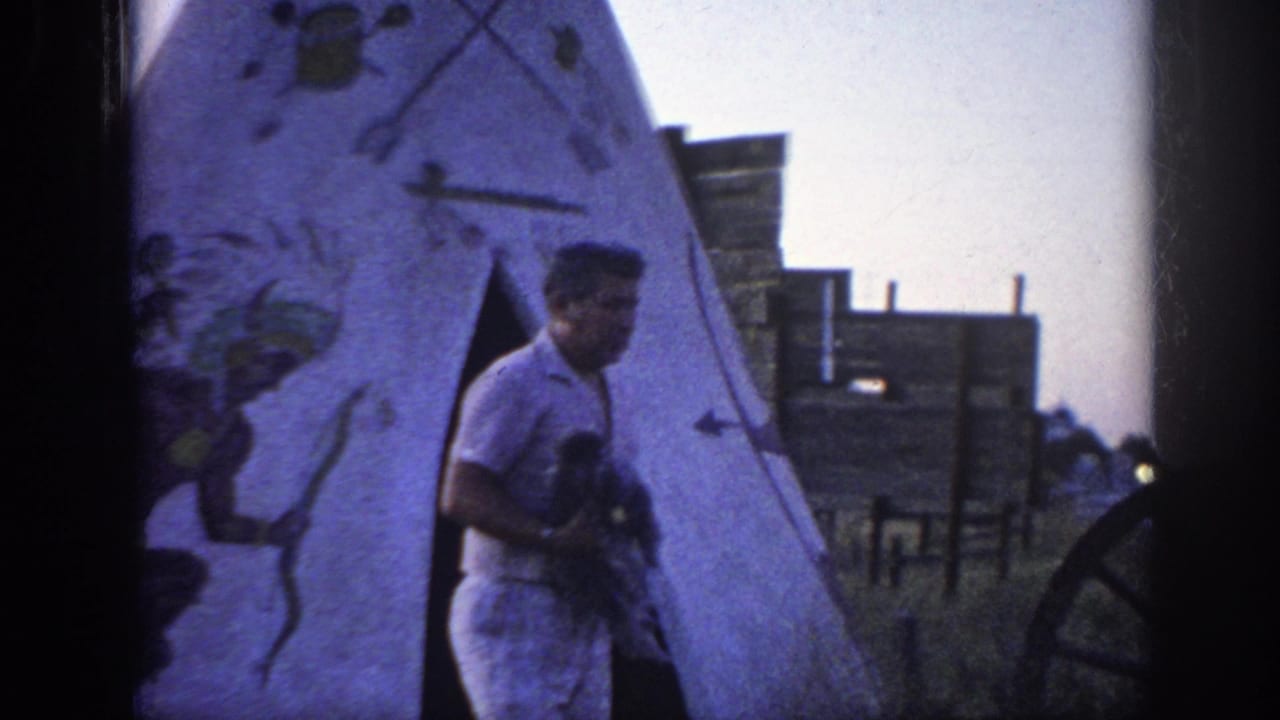Man with poodle turns near the entrance of a painted teepee.