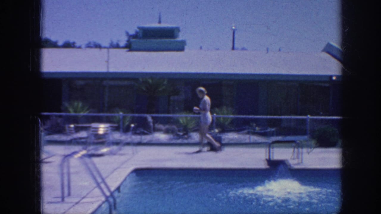 1963 Memphis frame with a woman moving along the motel pool deck, with pool water, railings, lounge chairs, and plantings visible.