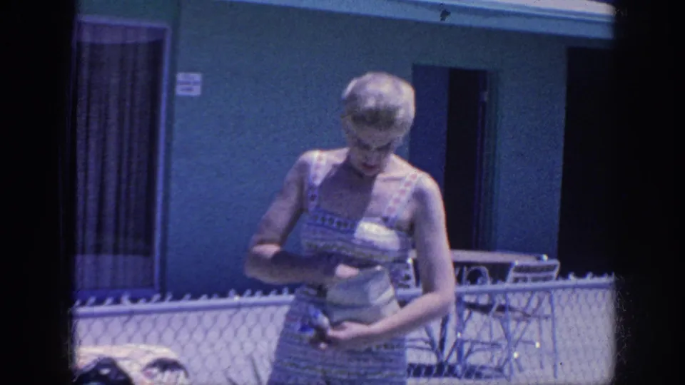 1963 Memphis frame showing the woman close to camera, looking down as she checks a small purse beside the motel pool area.