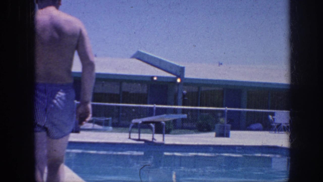 1963 Memphis home-movie frame showing a man in striped swim trunks near a motel-style outdoor pool and diving board.
