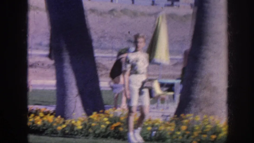 At the end of the 1963 Memphis clip, the woman walks away from the flower bed through a sunny palm-lined garden area.