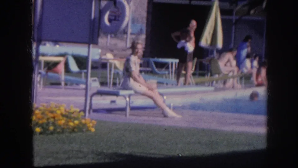1963 Memphis poolside scene at a Holiday Inn, showing a seated woman, relaxed guests, lounge chairs, flowers, and motel architecture.