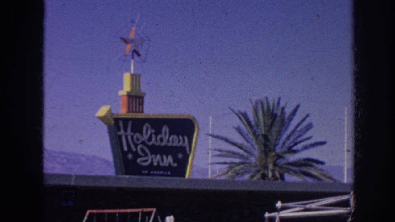Holiday Inn sign with star-topped tower against a blue sky and palm tree.