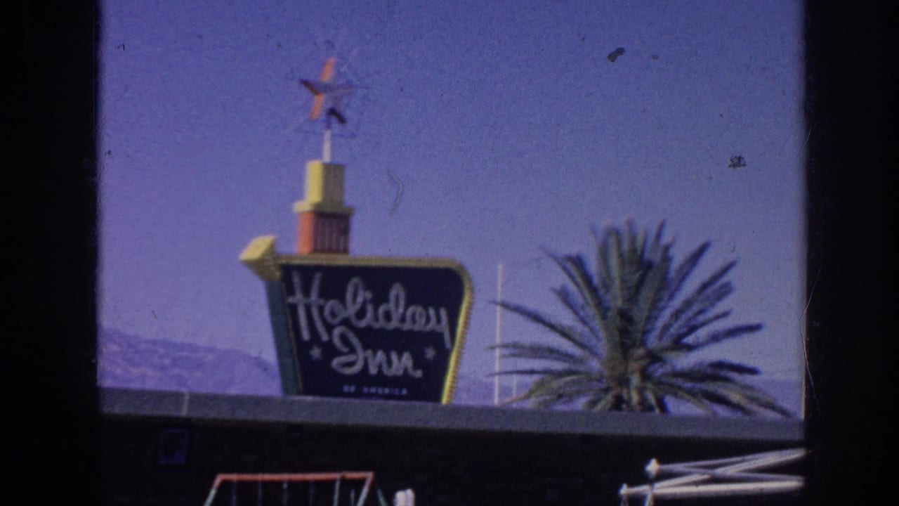 Holiday Inn sign repeated in the frame with palm fronds and blue sky.