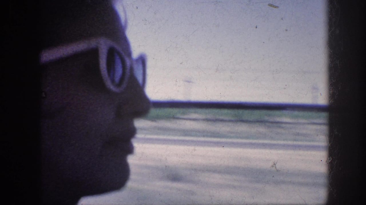 1963 Memphis-area 8mm frame showing a silhouetted passenger in white sunglasses looking out from a moving car.