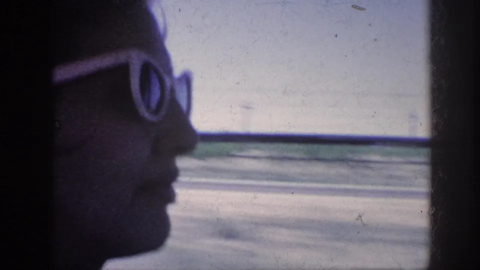 1963 Memphis-area 8mm frame showing a silhouetted passenger in white sunglasses looking out from a moving car.