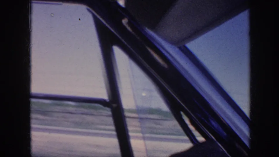 Interior 8mm view from a moving car, with window framing and roadside blur visible near Memphis in 1963.