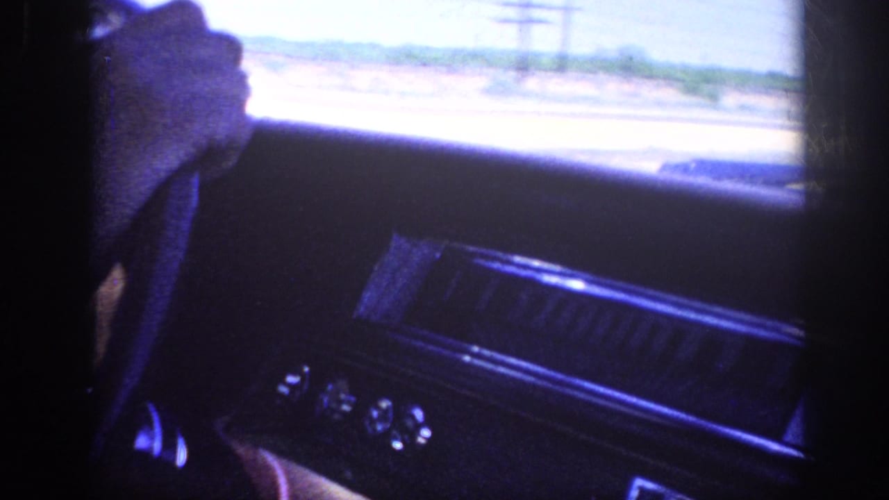 Car dashboard and passenger-side window area with open terrain and power lines outside.