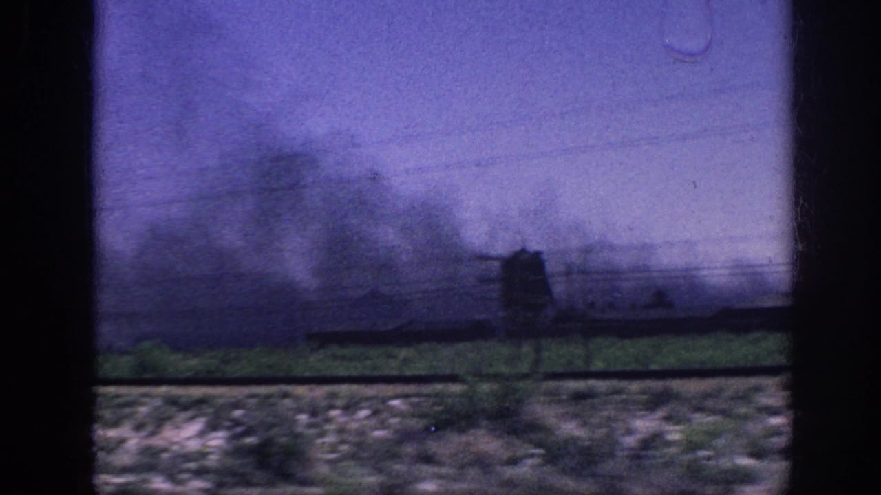 8mm home movie, c.1963 Memphis, Tennessee — dark smoke columns rise over flat scrubland with silhouetted utility poles, shot through a moving vehicle window.