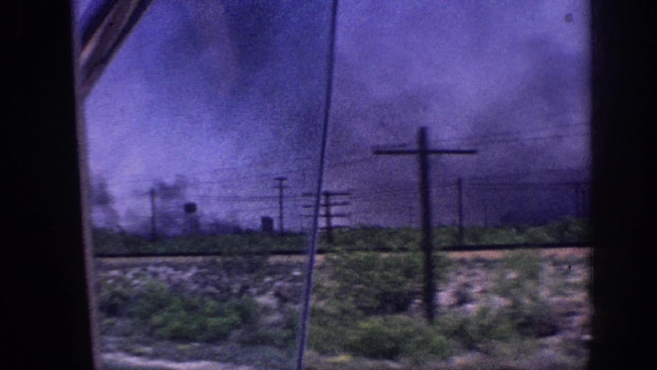 8mm home movie shot from inside a moving car showing a purple-hued storm sky over flat rural landscape near Memphis, Tennessee, circa 1963, with utility poles and a distant water tower visible.