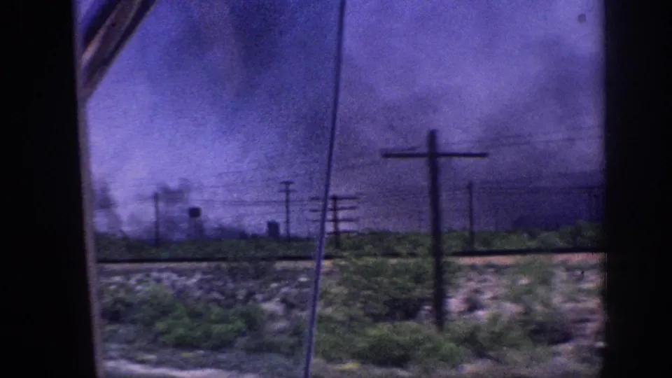 8mm home movie shot from inside a moving car showing a purple-hued storm sky over flat rural landscape near Memphis, Tennessee, circa 1963, with utility poles and a distant water tower visible.
