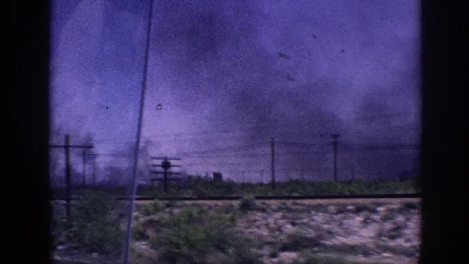 8mm archival footage from inside a moving car of a darkening storm sky with heavy cloud formations and utility poles across flat terrain, consistent with Memphis Tennessee area circa 1963.