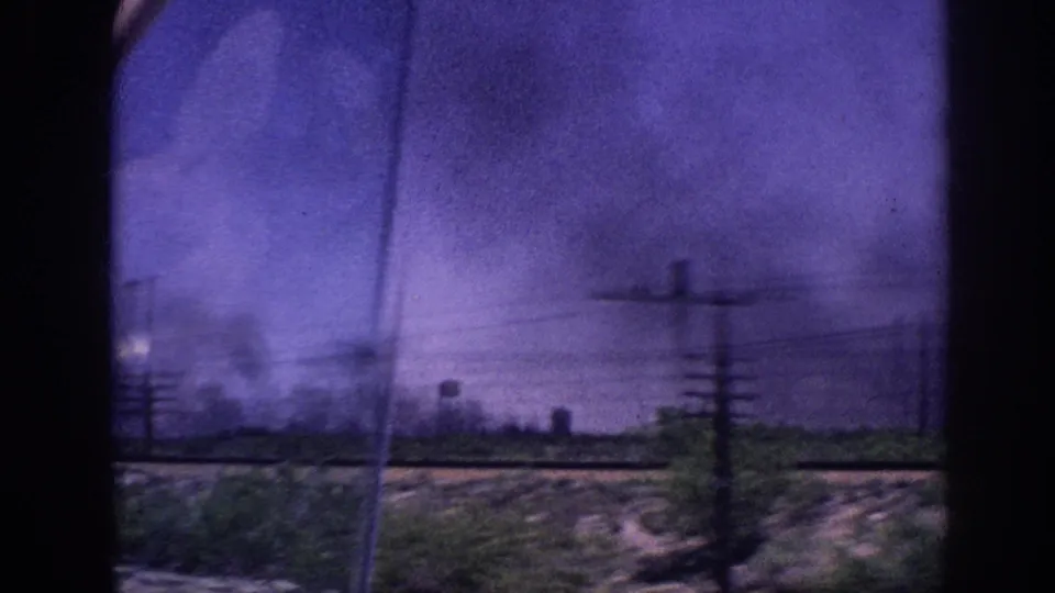 8mm home movie of heavy storm clouds over flat terrain near Memphis, Tennessee, circa 1963, with utility poles, power lines, and a distant structure resembling a water tower.