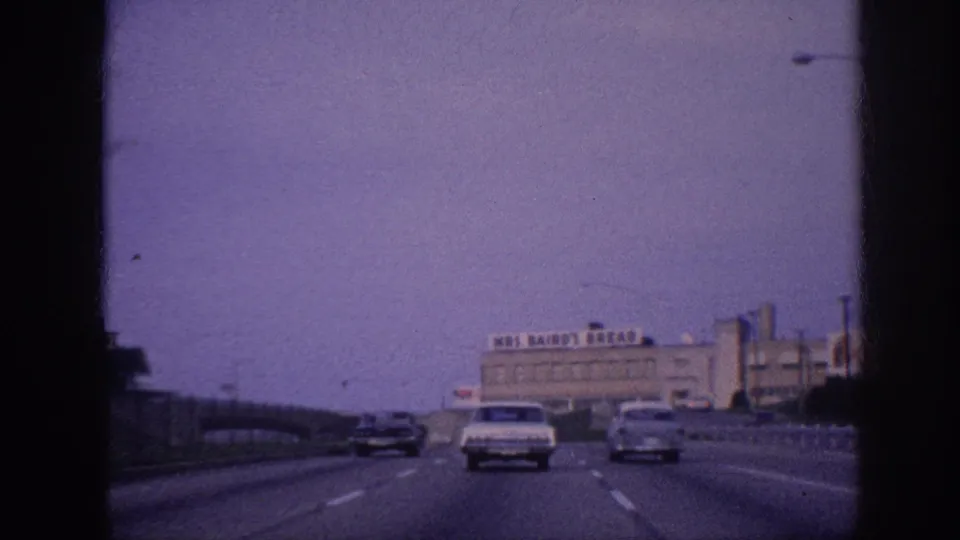 Memphis freeway, 1963; multiple vehicles ahead; Mrs. Bairo's Bread industrial bakery building and rooftop sign clearly visible on the right side of frame.