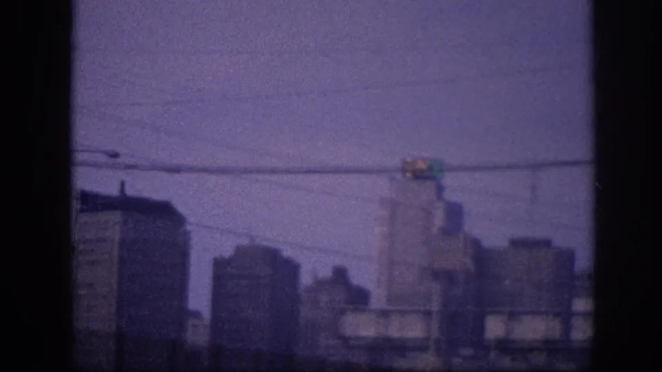 8mm home movie frame c. 1963 showing a downtown skyline, believed to be Memphis, with overhead power lines and a traffic signal visible.