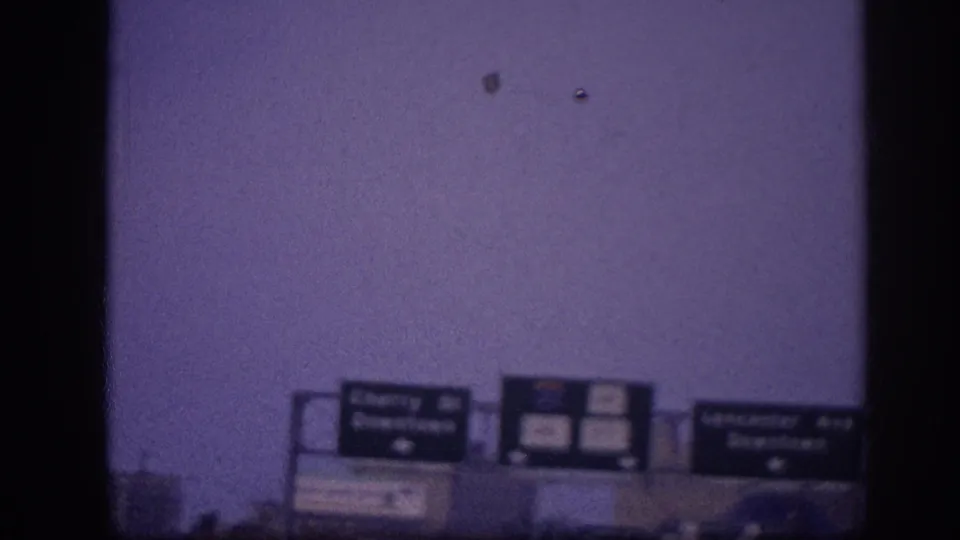 Overhead Memphis highway signage appears beside a dark film-frame edge, with the roadway scene mostly obscured below.