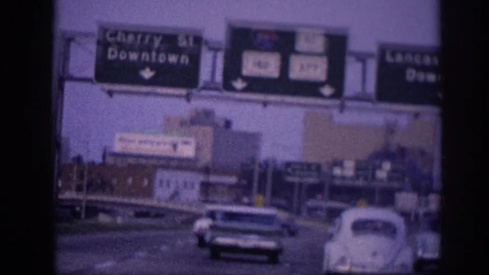 1963 Memphis highway view with mid-century cars traveling under Cherry Street and Lancaster Avenue Downtown signs, including a white Volkswagen Beetle.