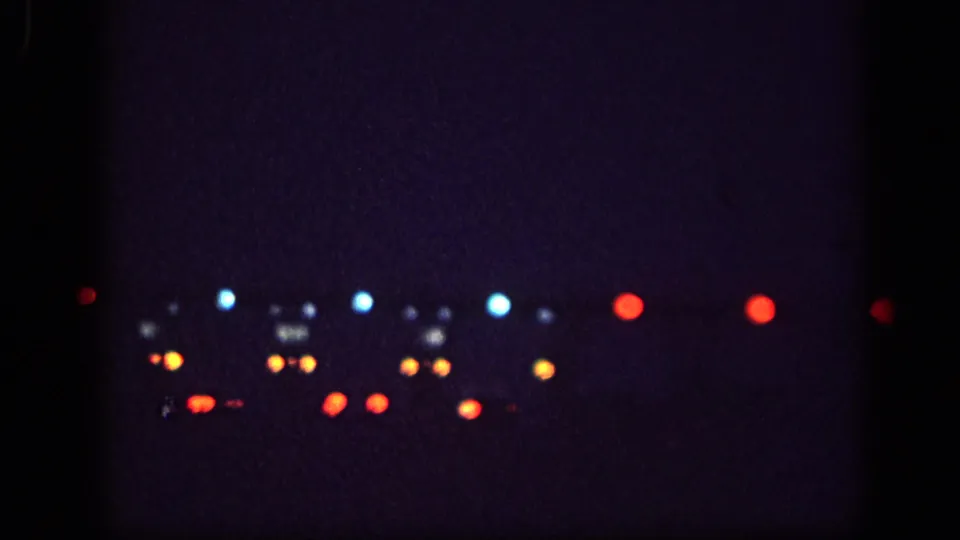 8mm footage transitioning to nighttime abstract: blurred bokeh lights in red, blue, and amber, likely distant traffic or city lights, Memphis area 1963.