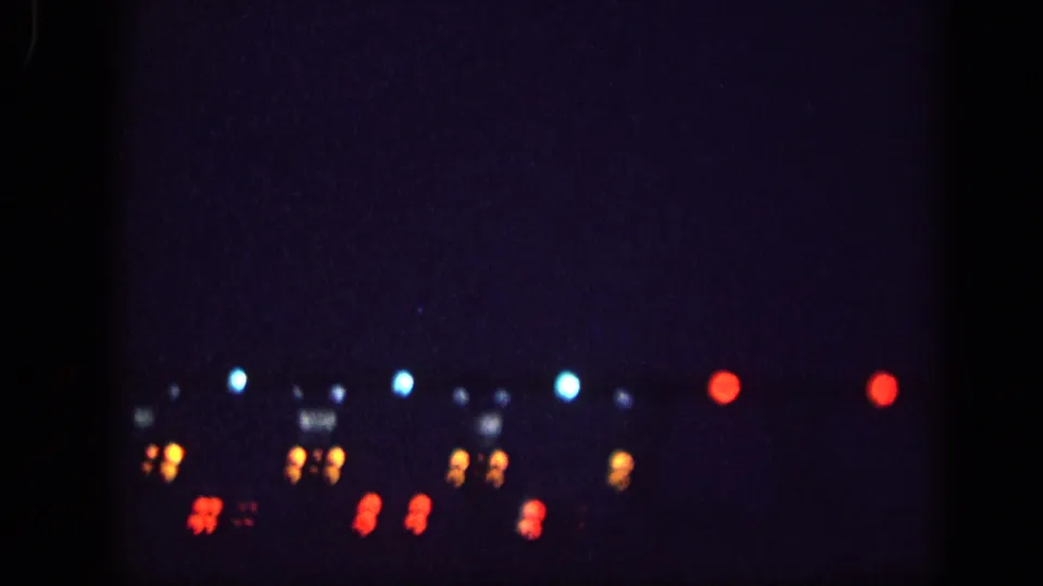 8mm night footage showing rows of bokeh lights in blue, amber, and red; light clusters may be vehicle headlights or taillights, Memphis area 1963.