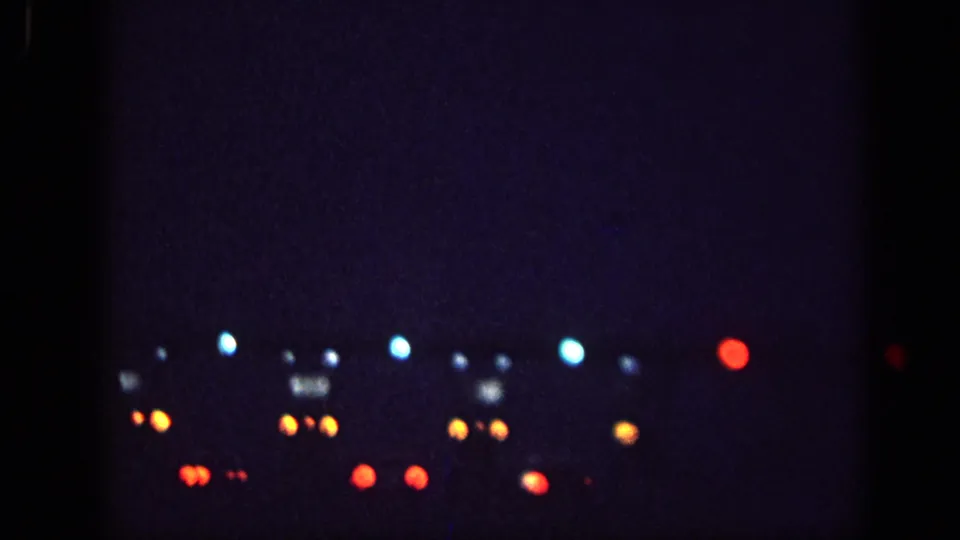 8mm night footage showing another arrangement of bokeh light orbs in blue, red, and amber clusters, consistent with Memphis 1963 nighttime driving record.