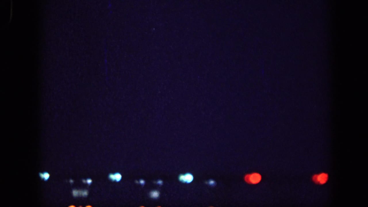 8mm home-movie frame from 1963, likely Memphis, Tennessee: a horizontal row of out-of-focus blue, white, and red lights across a deep blue night sky.